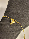 Gold puffy heart charm bracelet worn on wrist showing heart pendant detail