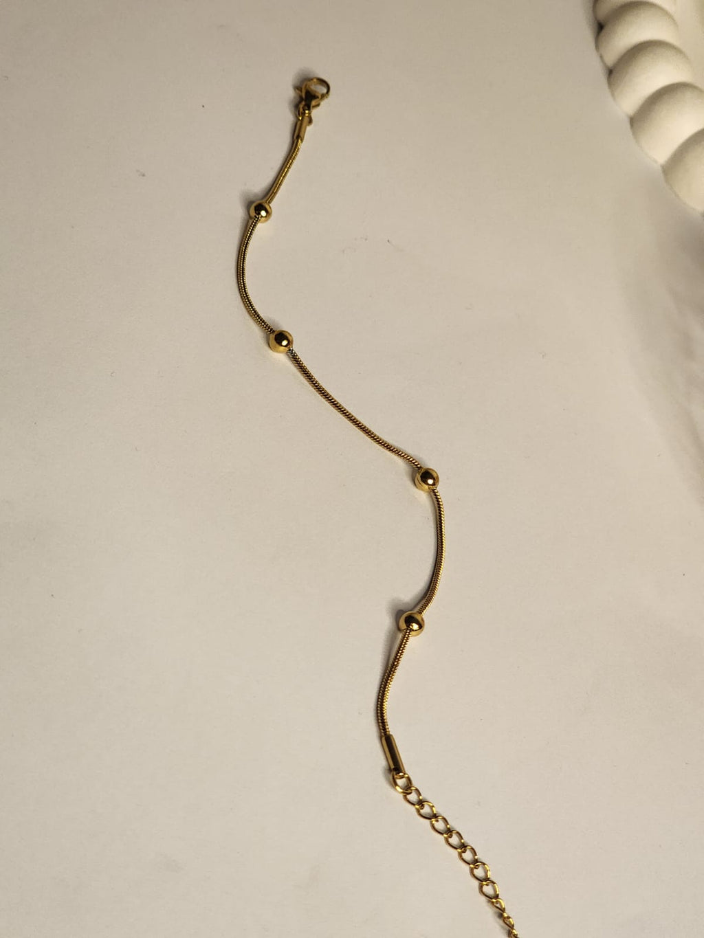 Gold snake chain ball station bracelet showing extender chain detail