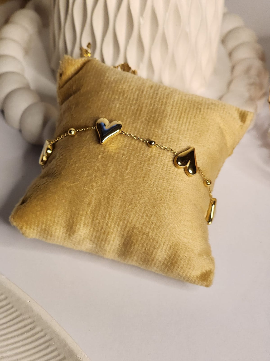 Multi heart gold chain bracelet displayed on velvet cushion