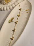 Multi heart gold chain bracelet laid flat on white feather tray
