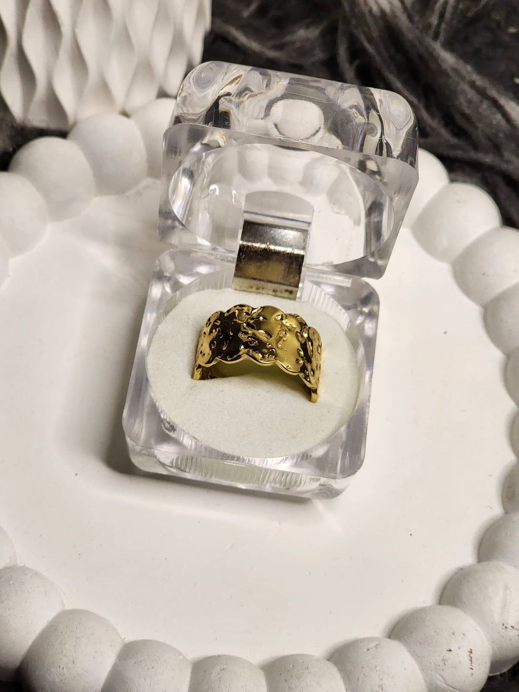 Wide gold band ring with raised floral and vine engravings in a clear gift box