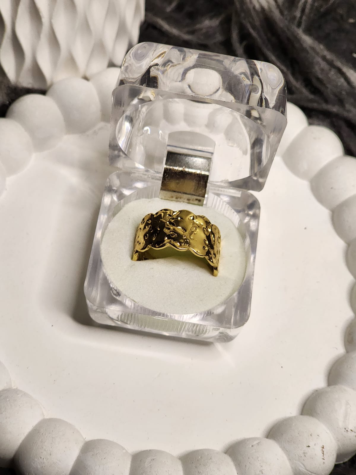 Wide gold band ring with raised floral and vine engravings in a clear gift box