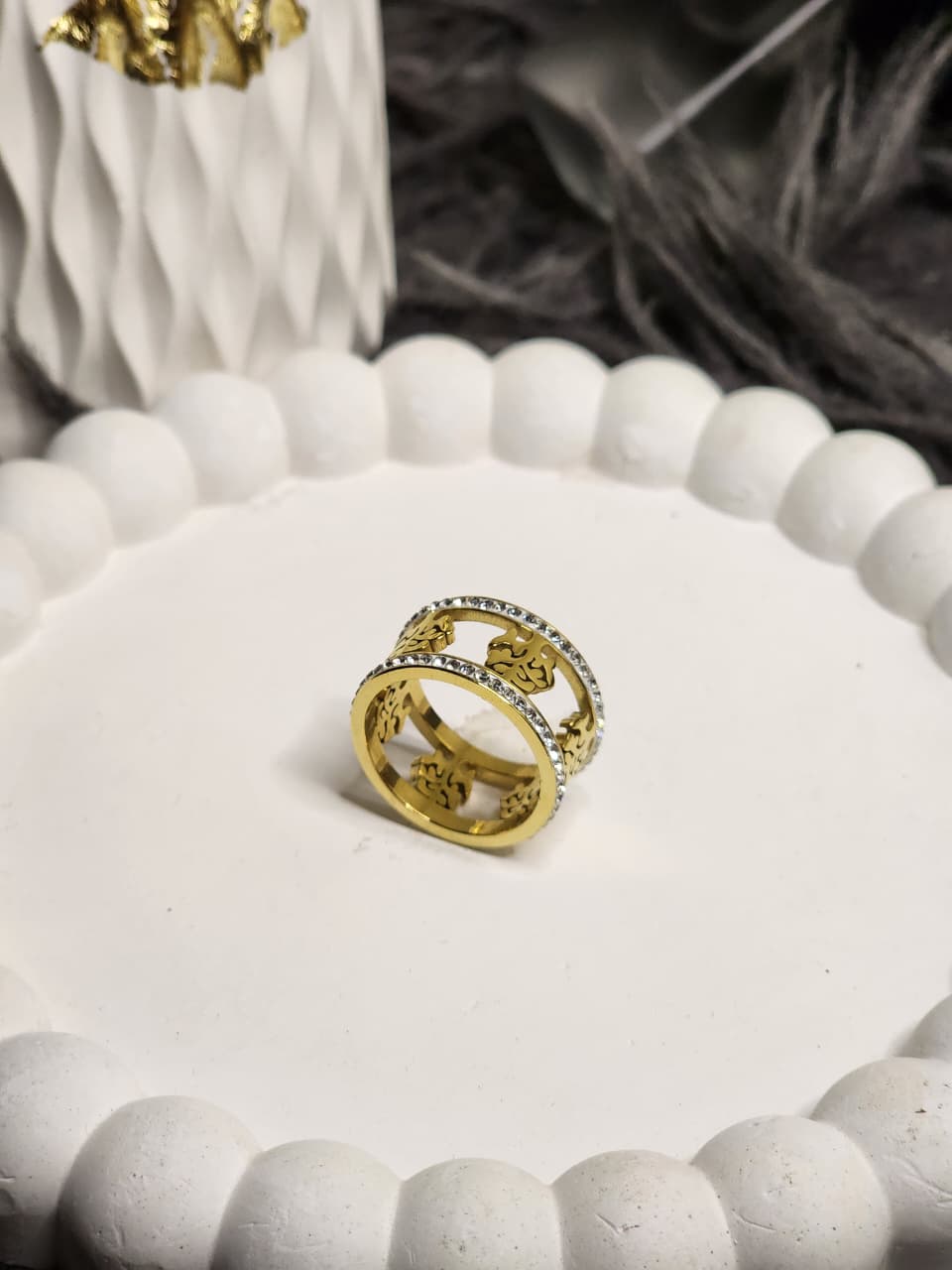 Wide gold floral cutwork ring with crystal edges on white display stand