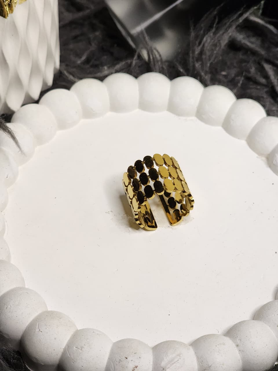 Gold multi-row disc ring with antique coin-inspired design on white display stand