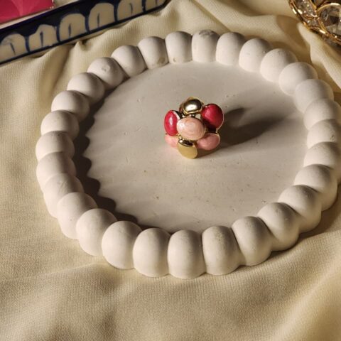 Close-up of a high-quality, bold gold statement ring with a large cluster of smooth, multi-tonal pink and polished gold cabochons.