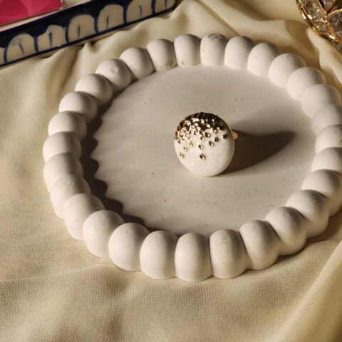 Close-up of a modern gold statement ring featuring two smooth, organic pebble-shaped stones in deep emerald green and pure white.