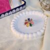 A colorful gold-finish statement ring featuring a multi-color rainbow petal design on a white decorative tray.