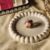 A top-down shot of a gold-finish statement ring featuring a cluster of textured gold petals and smooth pink enamel petals on a white decorative tray.